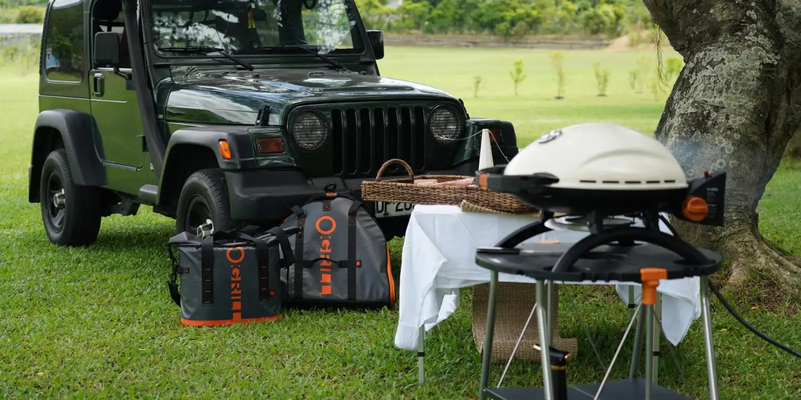 An cream o-grill 900 on its stand at a campsite