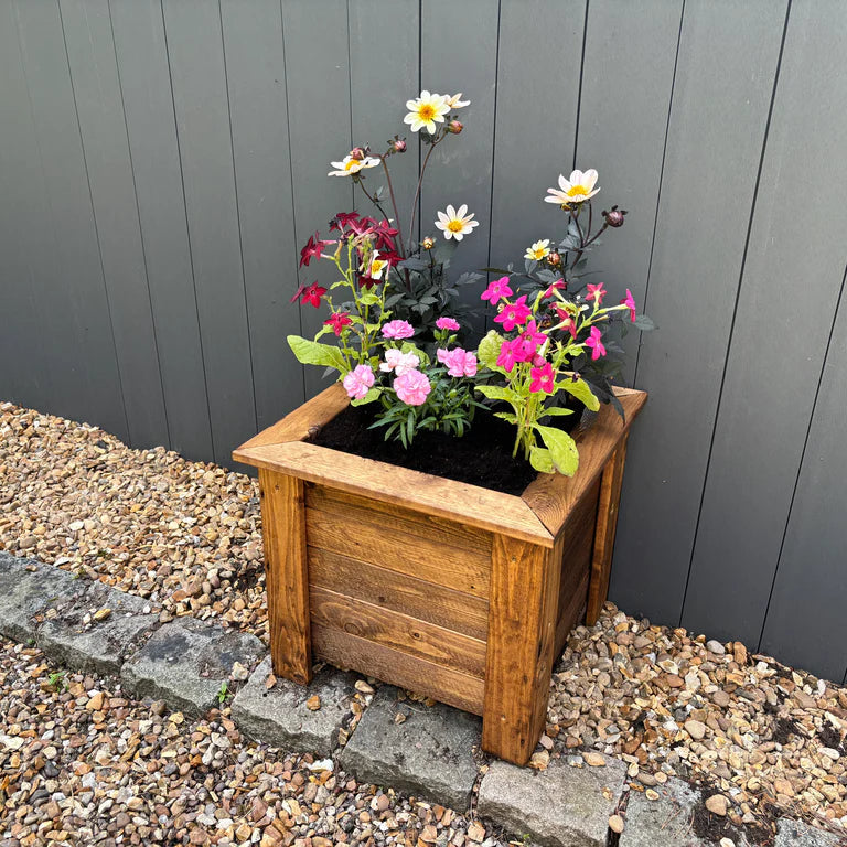 PRESTBURY RAISED SQUARE PLANTER LARGE - planted, grey fence, gravel, stone pavers, flowers. 