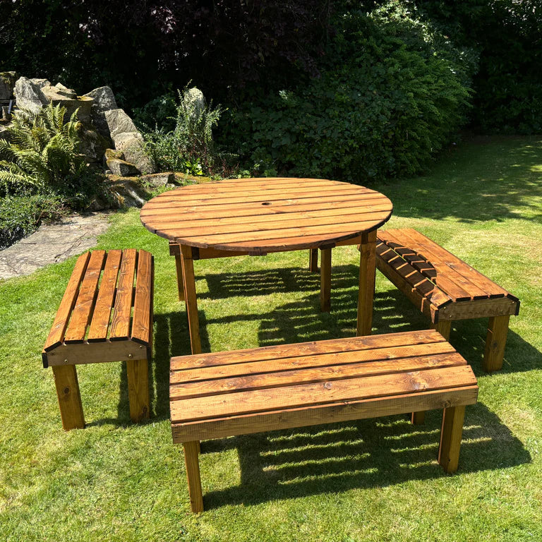 KNIGHTS EIGHT SEATER ROUND TABLE SET - Side view of the table set in the sun, next to pond and bushes. 