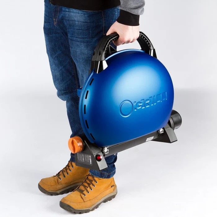 A blue O-Grill 500 being carried by its carrying handle