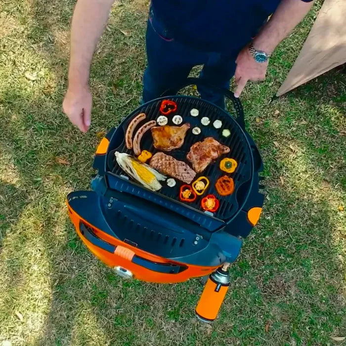 The O-Grill 500 in orange being used to fry some sausages, chicken thighs and vegetables