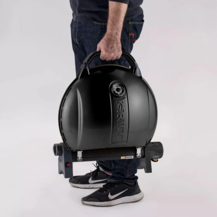 A black O-grill 900 being carried by its handle against a white background