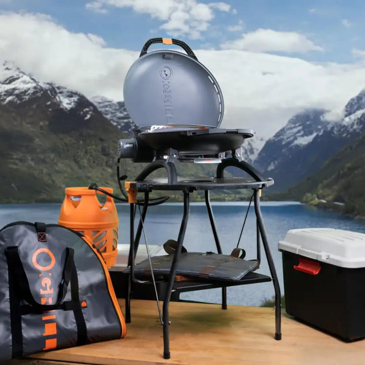 A promotional image of an o-grill stood on the stand with all accessories around it